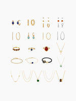 A flat-lay grid display of the earring assortment included in the kit, showing pairs of gold and silver earrings (studs, hoops, and drops) arranged neatly.