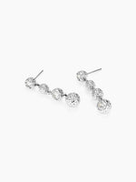 A side view of the silver layered ball drop earrings resting on a white surface, showing the ear posts and the cascading stone structure.