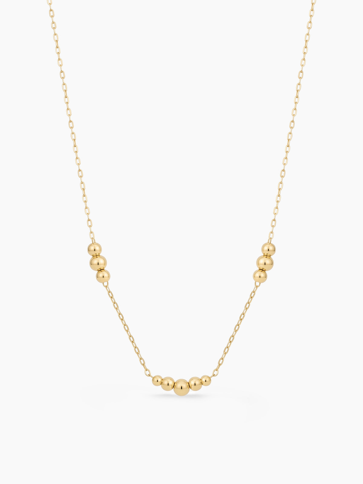 Gold necklace with small beads on a white background