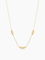 Gold necklace with small beads on a white background