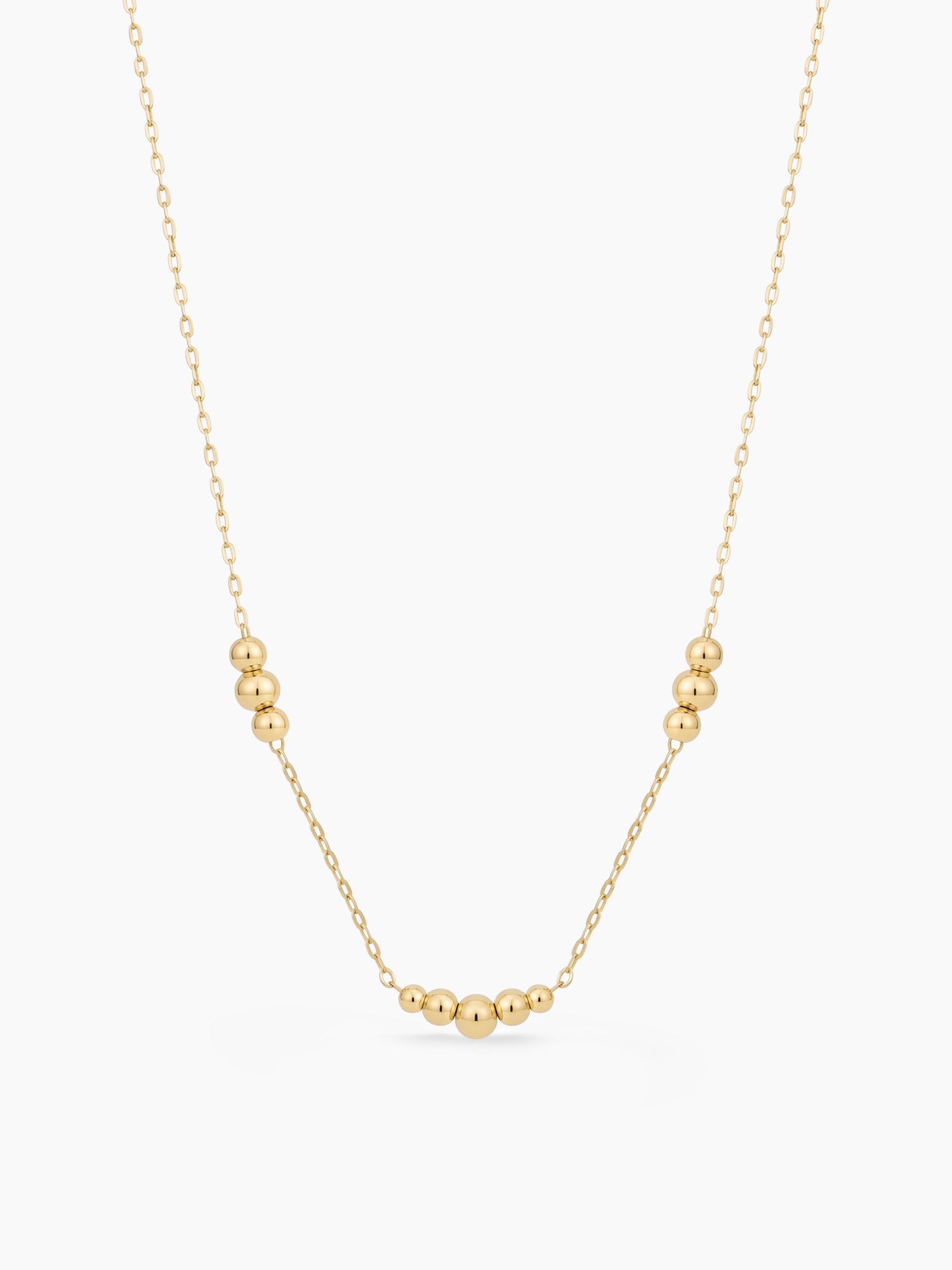 Gold necklace with small beads on a white background