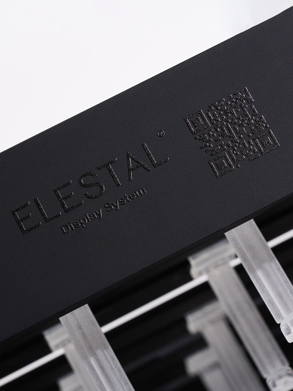 A macro close-up of the black wooden base featuring the engraved "ELESTAL" brand logo and text, showing the clear hooks inserted above.