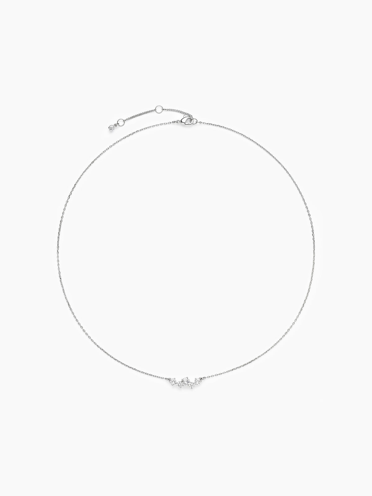 The silver CZ cluster chain necklace laid out in a perfect circle on a white background, highlighting the thin chain and central stones.