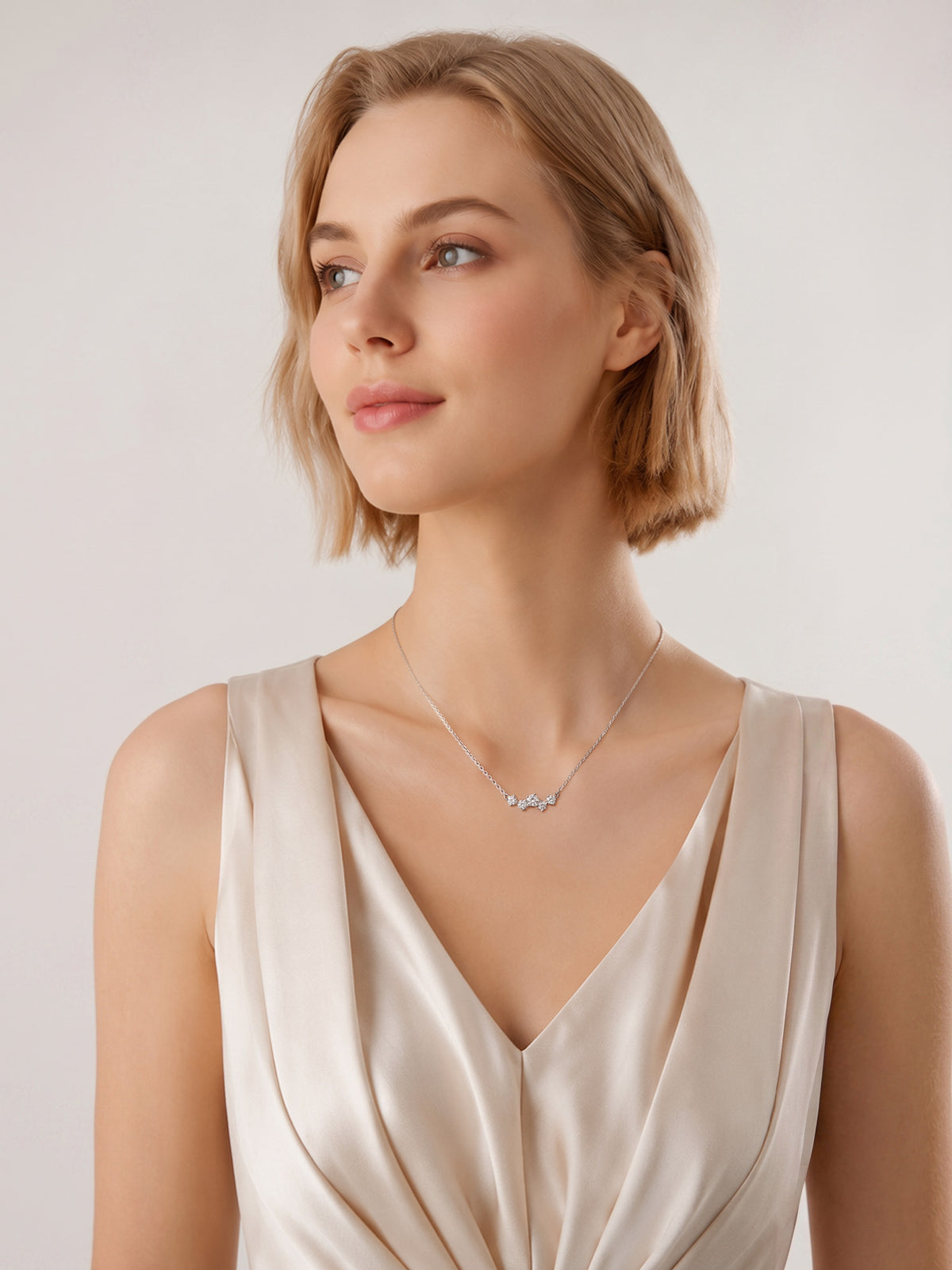 Close-up of a model's neck showcasing a delicate silver multi-stone necklace. Lightweight sparkle for bridal, layering, or casual office looks.