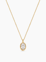 A delicate gold chain necklace featuring a bezel-set oval cubic zirconia pendant, displayed on a plain white background.