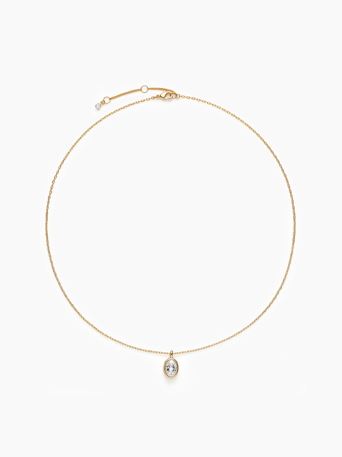 The gold oval CZ necklace laid out in a perfect circle on a white background, highlighting the thin chain and central pendant.