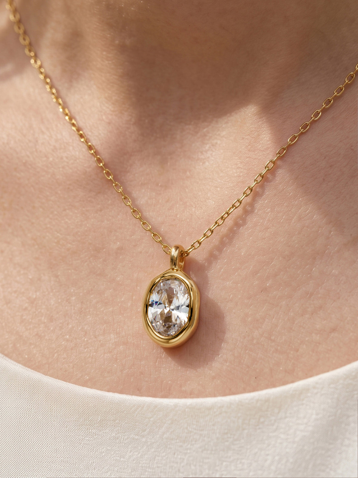 Close-up of a model's neckline wearing the gold oval CZ pendant necklace, showcasing its sleek and elegant look against the skin.